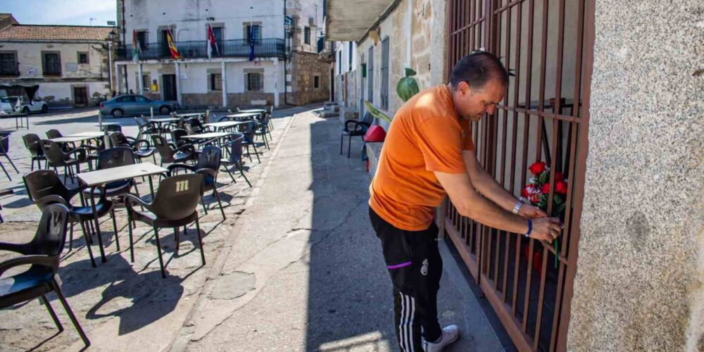 En la imagen un vecino coloca unas flores en la puerta del domicilio de la víctima, en Pelahustán. EFE/Ángeles Visdómine.