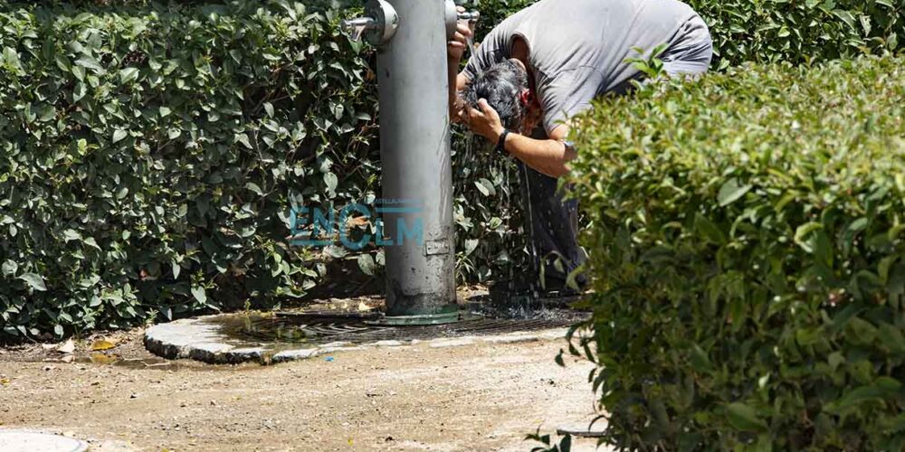 Hombre mojándose la cabeza en una fuente de Toledo, calor, verano