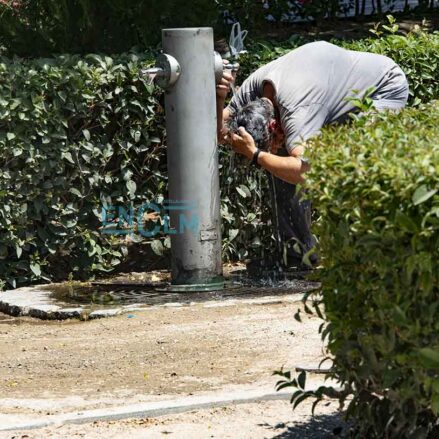 Hombre mojándose la cabeza en una fuente de Toledo, calor, verano