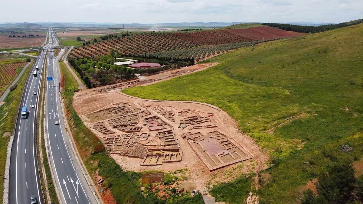 Imagen aérea de la parte excavada del Cerro de las Cabezas. Al fondo, su centro de interpretación