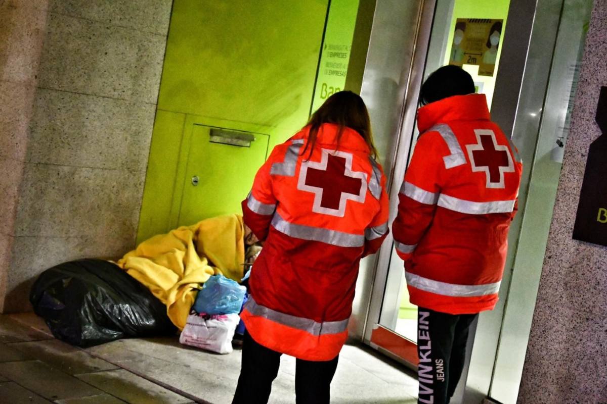 Imagen de archivo de dos voluntarios de Cruz Roja atendiendo a una persona sin hogar