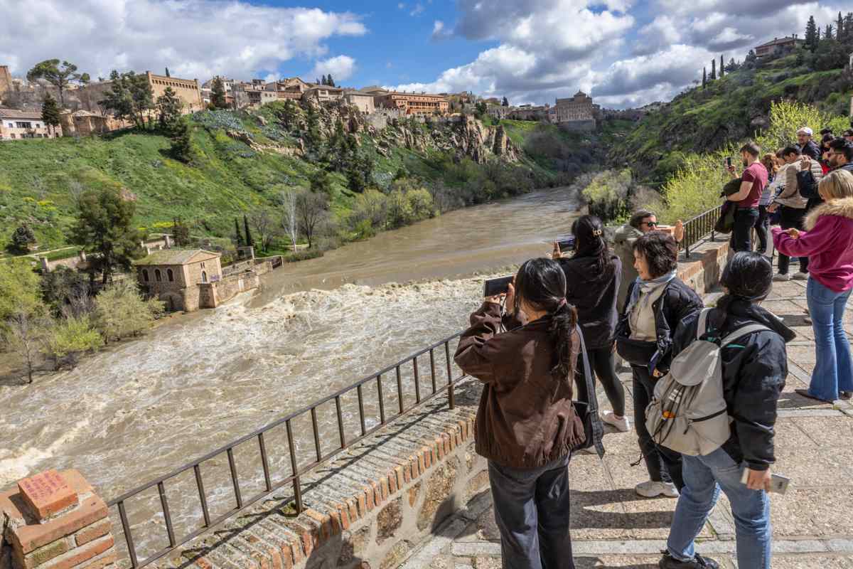 Turistas y curiosos fotografían la subida del Tajo en Toledo. Foto: EFE/Ángeles Visdómine.